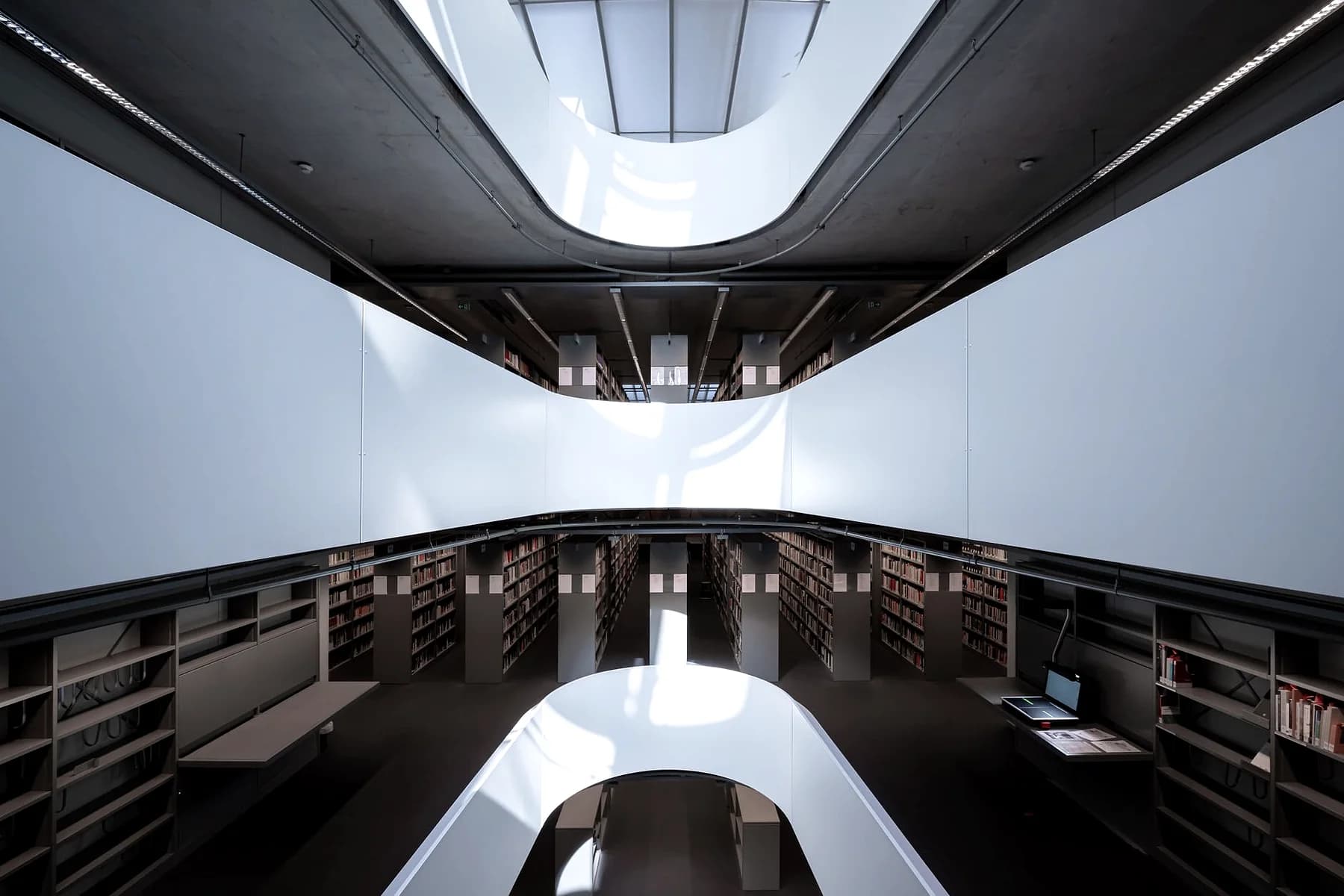 Interior of a modern library with tiered shelving and a skylight.